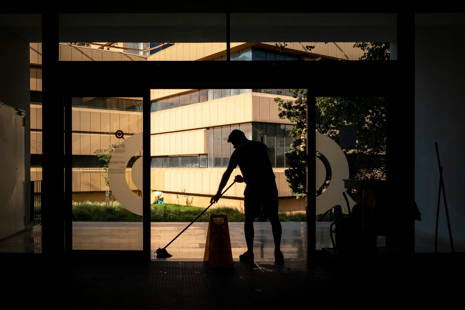 Silhouette of a person mopping a glass entrance